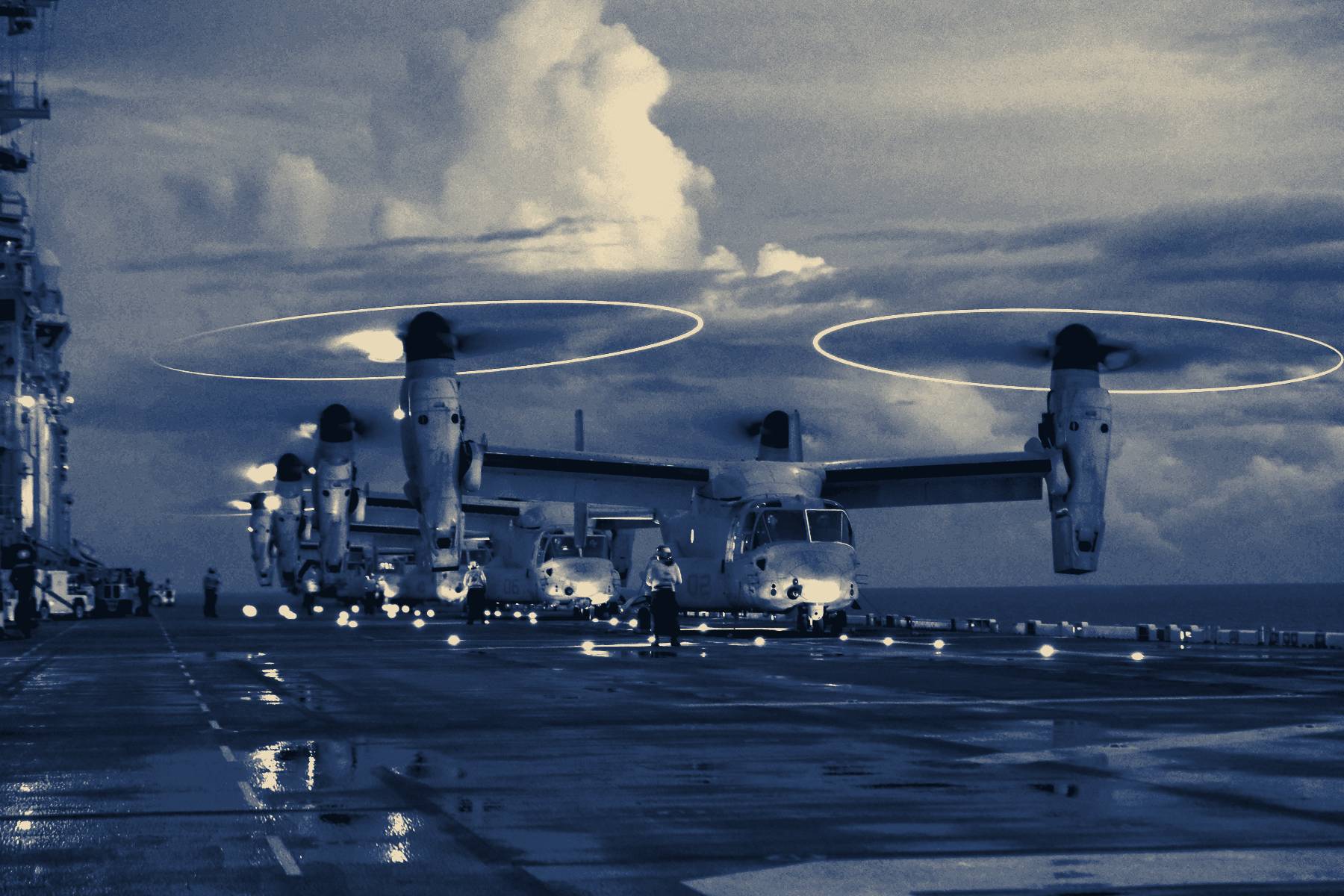 A flight-deck director signalling a helicopter with light wands at night