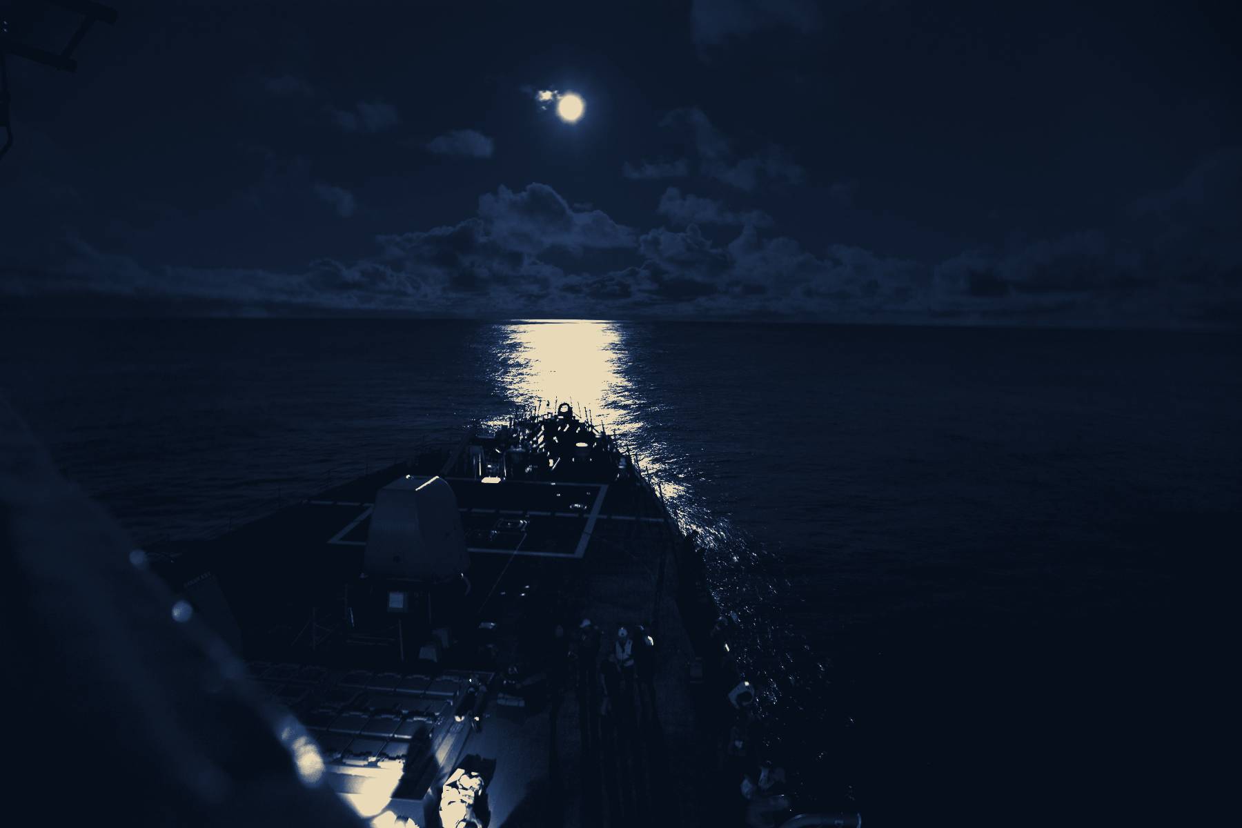 A destroyer's bow under a full moon on open sea